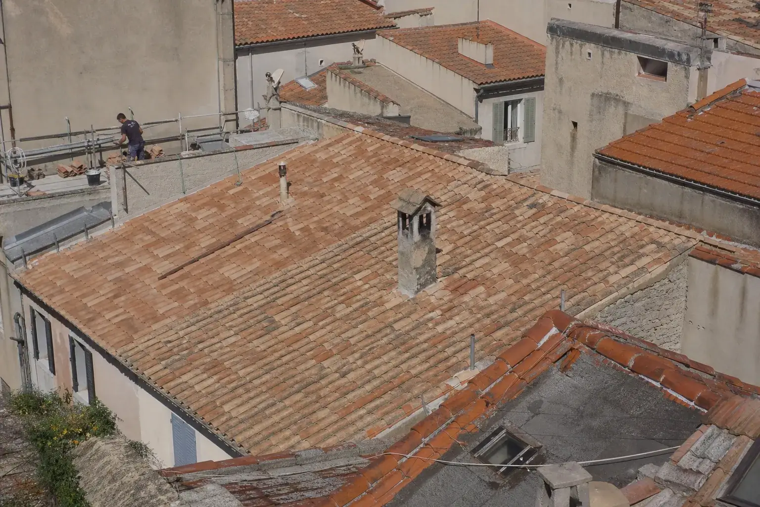 Toit repris en tuiles creuses de teinte vieillie pour se fondre exactement dans les toitures voisines d’un centre ancien provençal, sans rupture de couleur